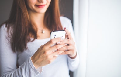 woman in a white shirt holding her cell phone in front of her