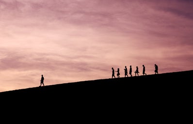 Silhouettes of people walking on a hill