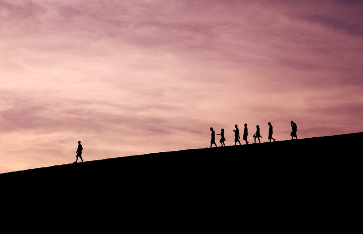 Silhouettes of people walking on a hill
