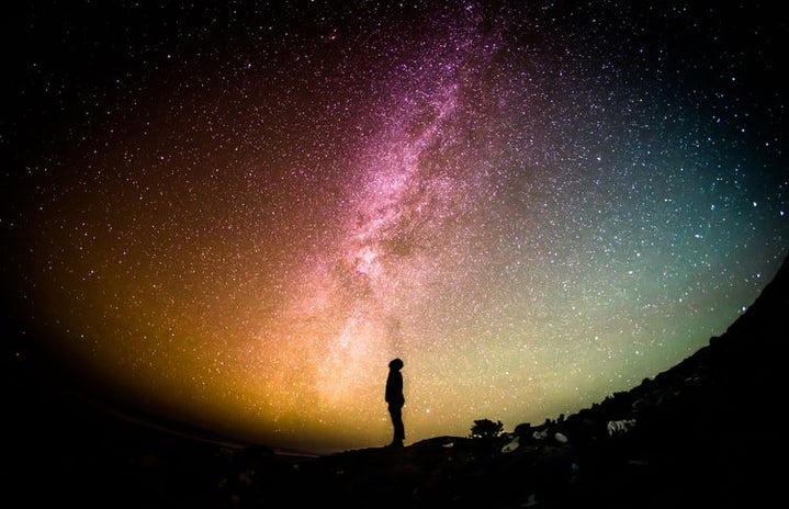 Silhouette of man in front of colorful, starry sky