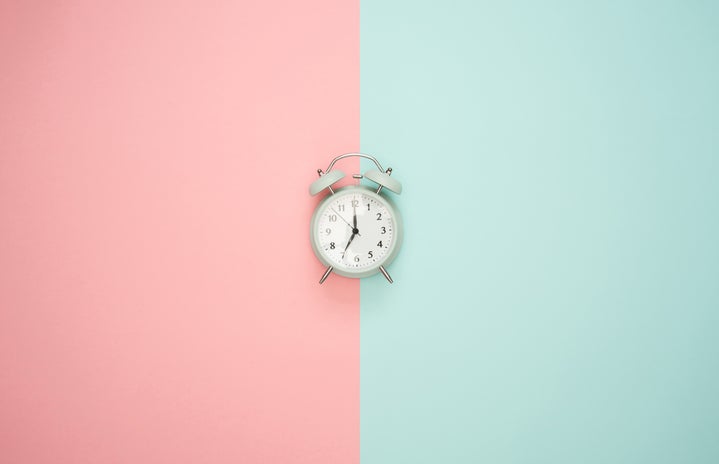 A clock in front of a pink and blue background