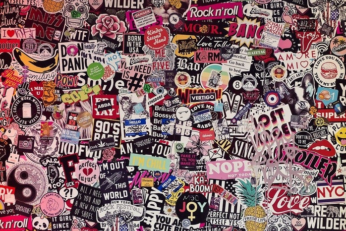 A bunch of stickers, all different sizes, colors, and designs, overlapping on a wall
