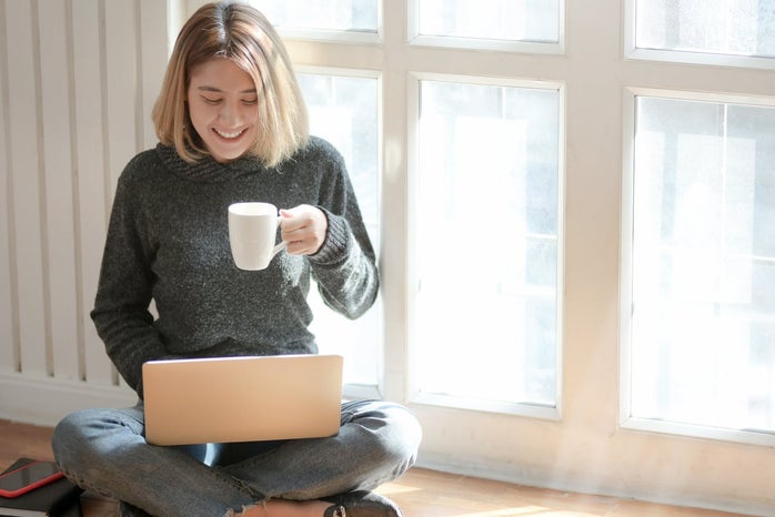 woman working on laptop while holding a mug