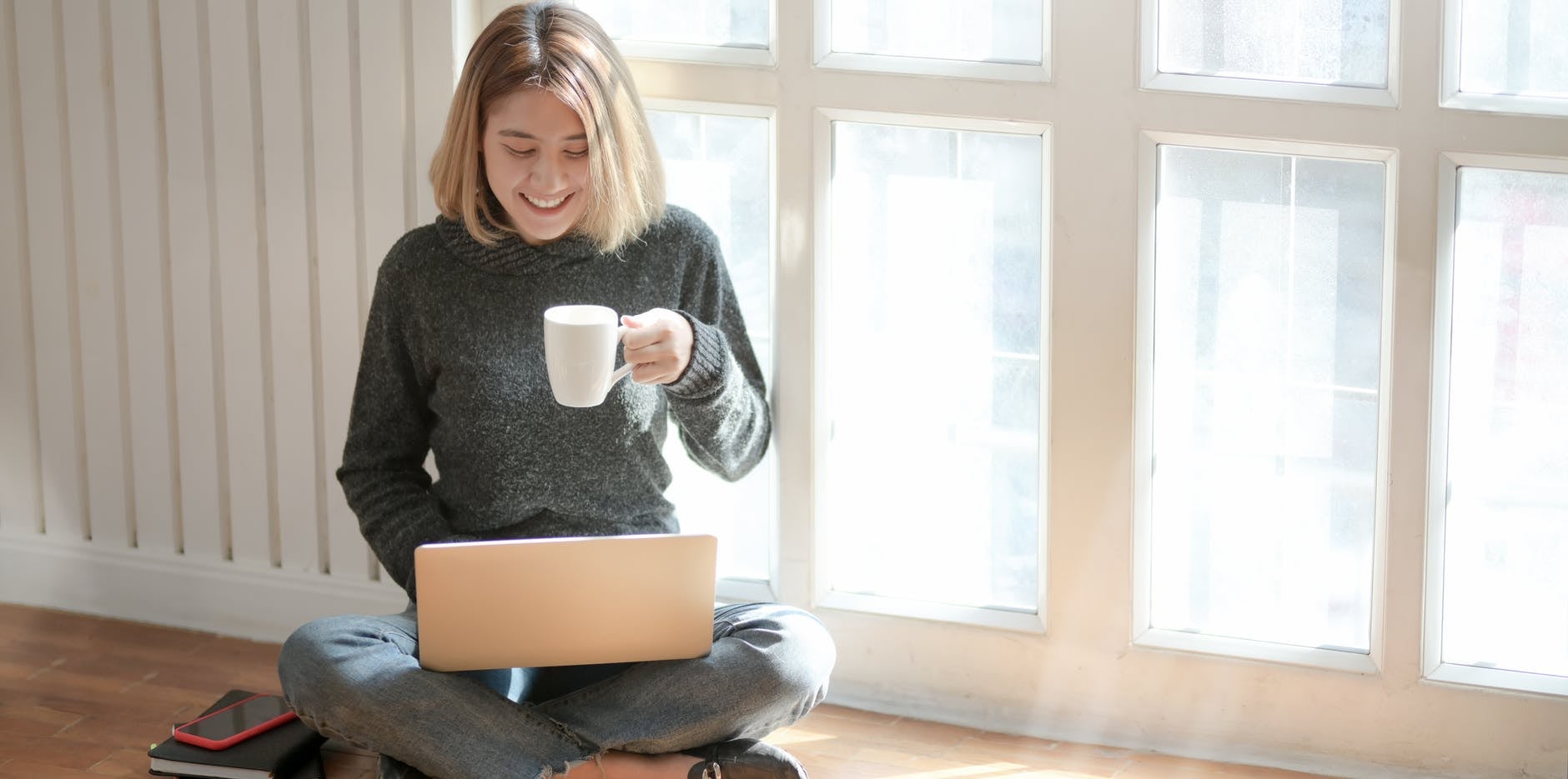 woman working on laptop while holding a mug