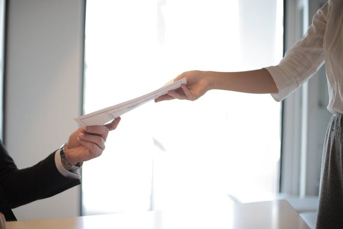 job applicant handing her documents and resume to employer during interview