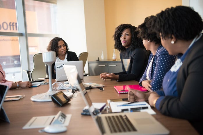 four women working at conference table job