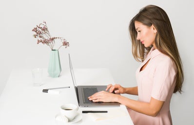 woman in pink dress working on laptop