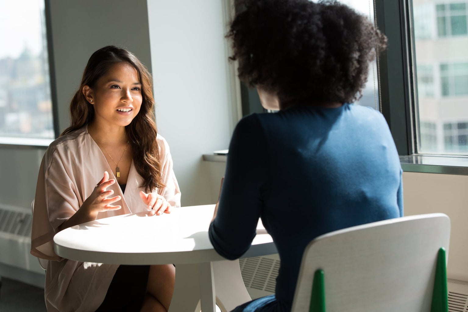 two women talking at a table together work business casual