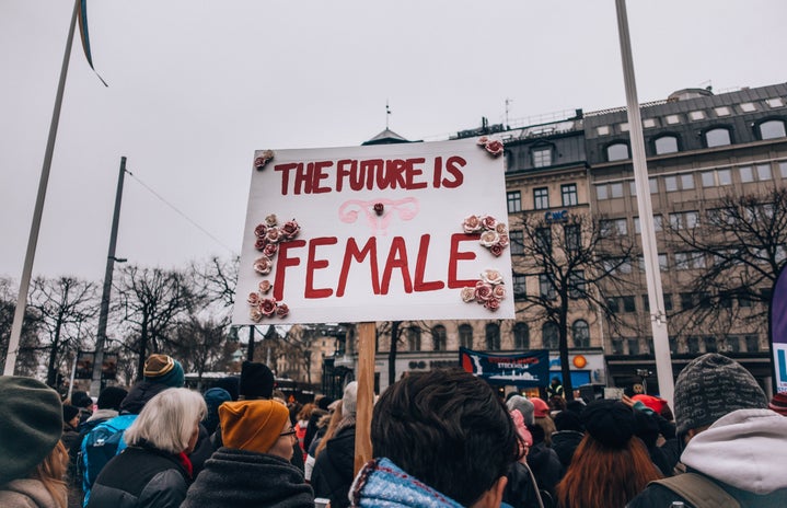 Crowd of women, one holding a sign that says "the future is female"