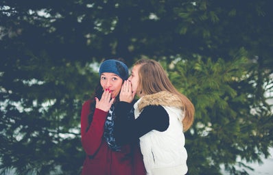 Woman whispering into other woman\'s ear