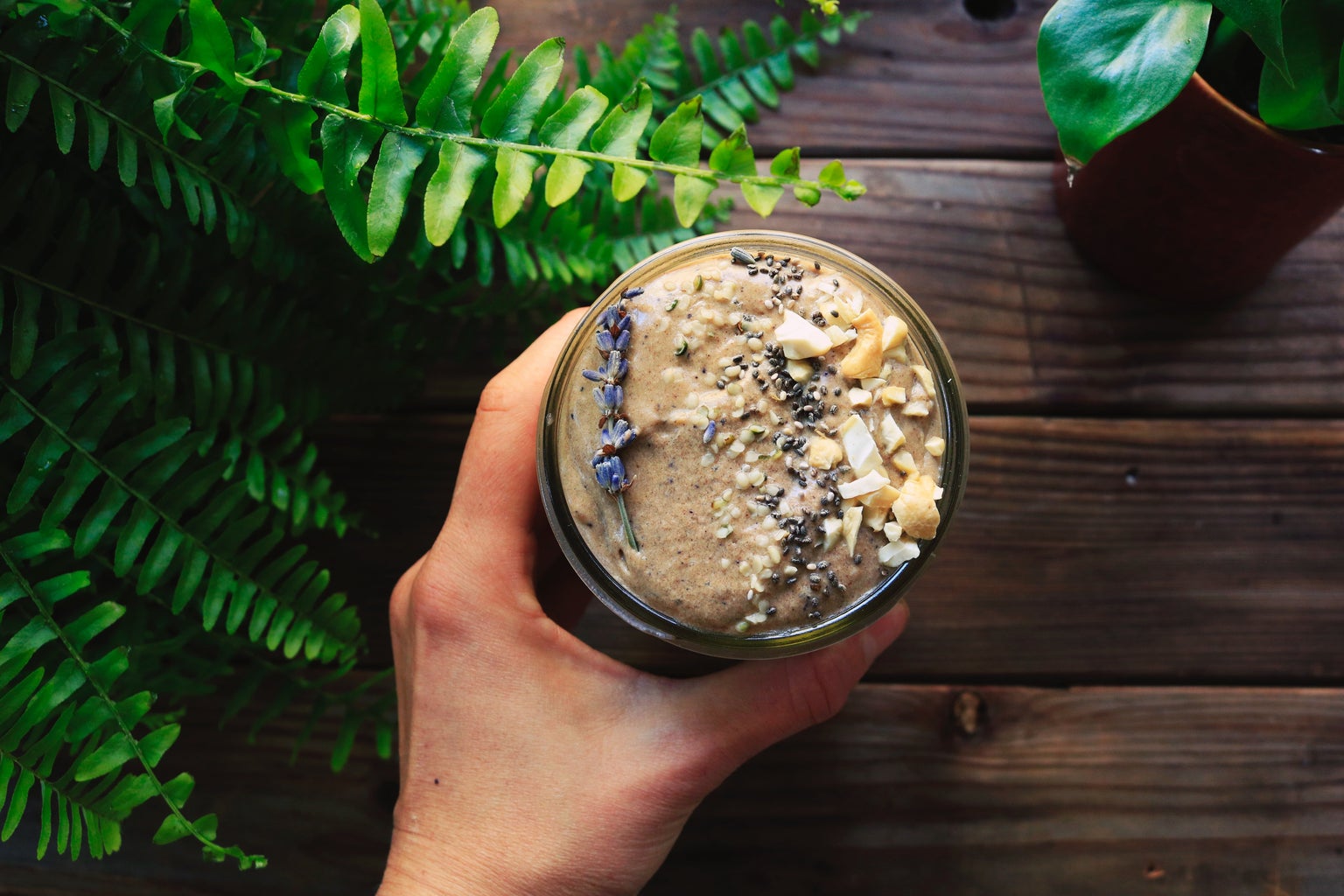 woman holding glass of smoothie with plants