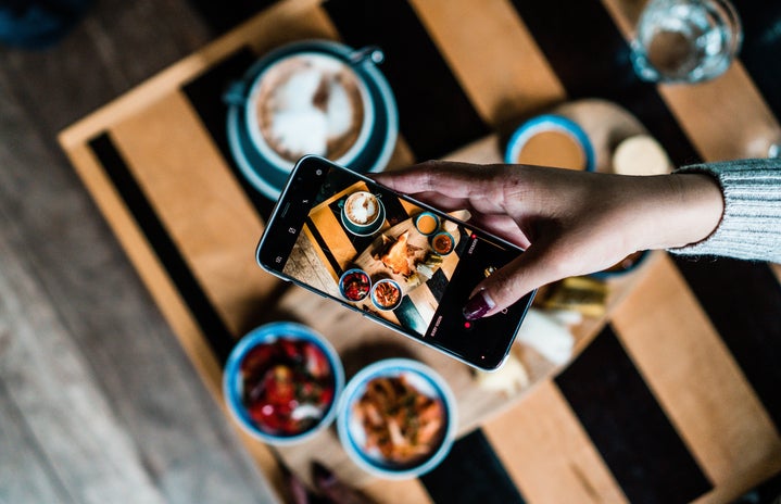 Person taking photo of food on table