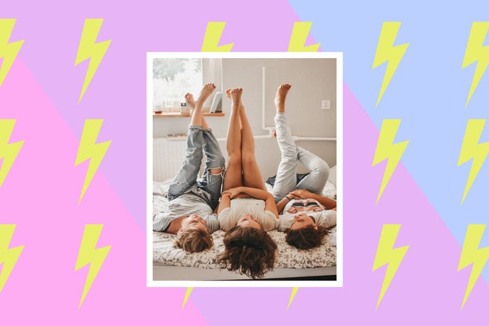 three women lay next to each other on a bed with their feet up in the air.