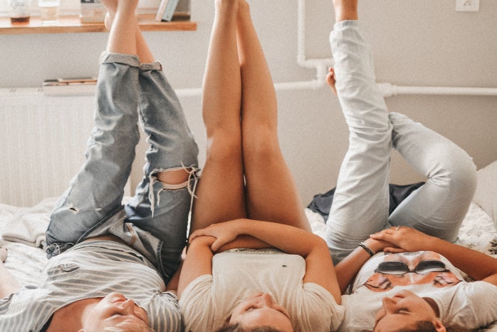 three women lay next to each other on a bed with their feet up in the air.