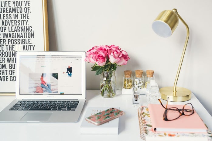 MacBook Air beside gold-colored study lamp and spiral books