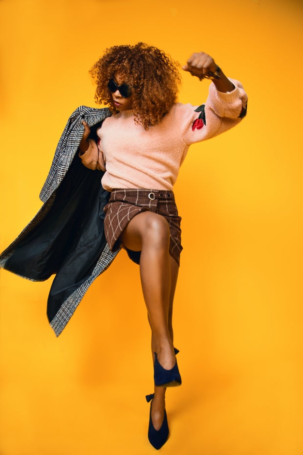 Woman wearing peach sweater and brown plaid skirt