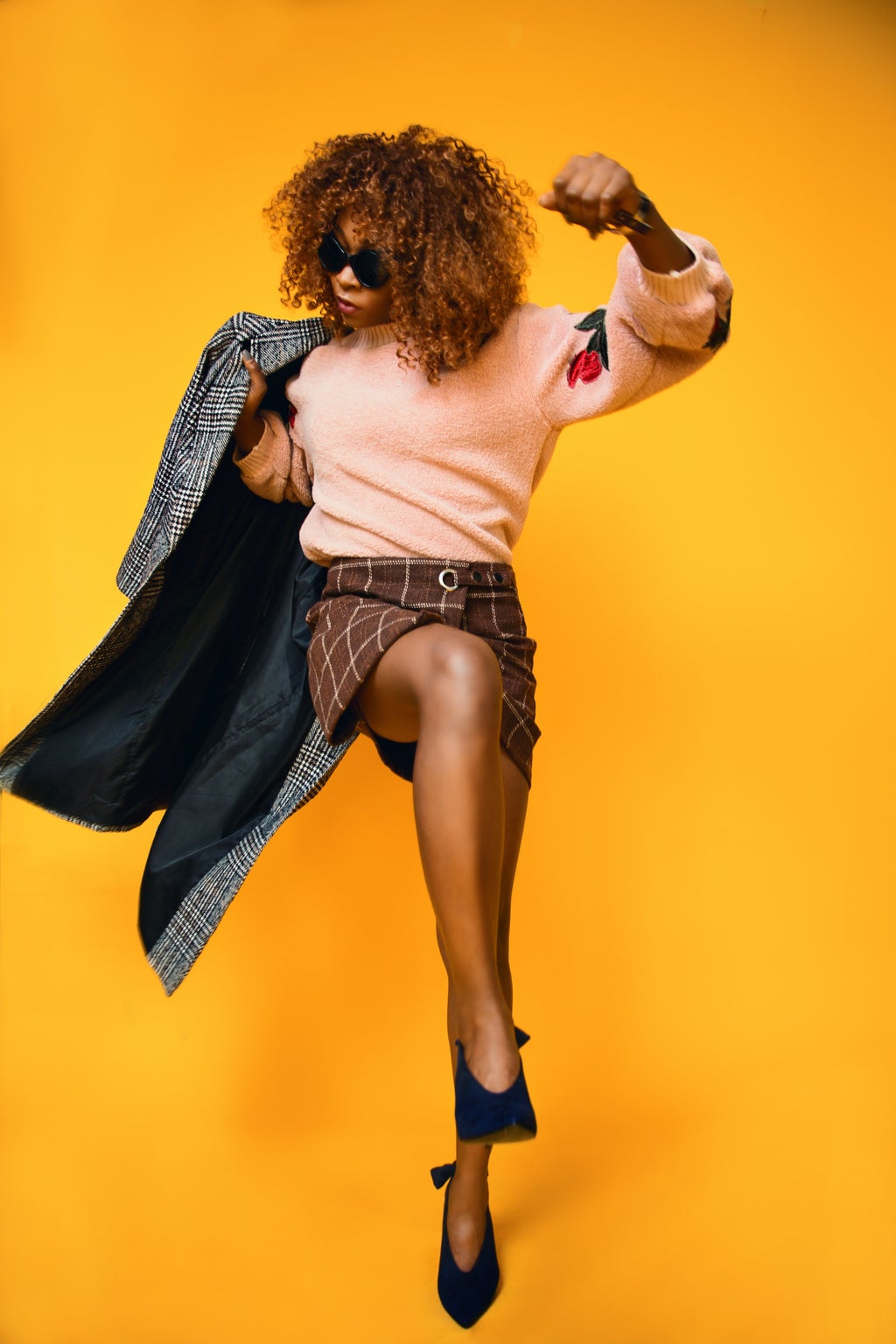 Woman wearing peach sweater and brown plaid skirt