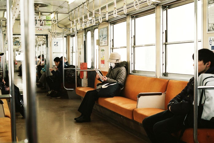 Masked person sitting on subway train car