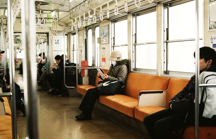Masked person sitting on subway train car