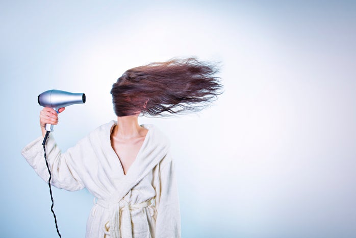 Girl with a hairdryer blowing her hair across her face