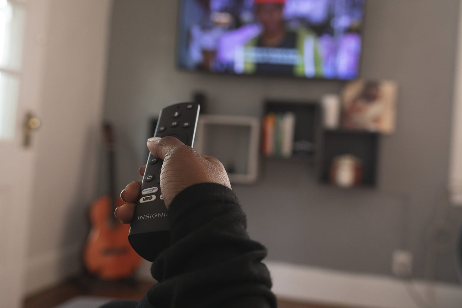 Hand holding remote pointed at tv screen