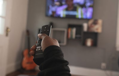 Hand holding remote pointed at tv screen