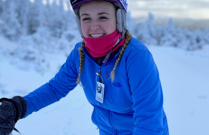 girl in blue jacket and skis smiling