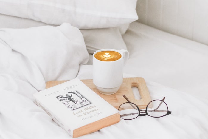 a bed with some books and a coffee