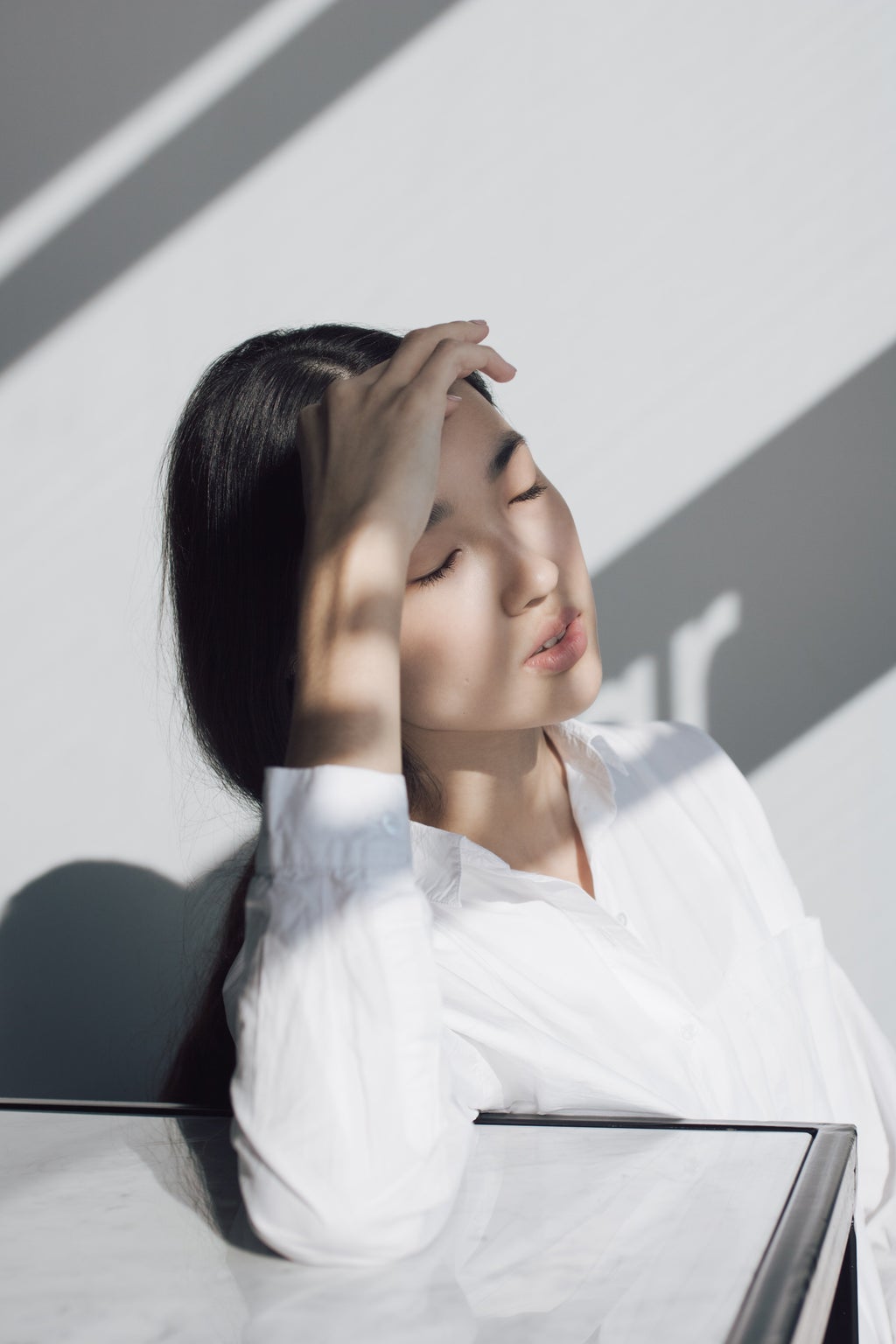 Asian woman leaning on white table