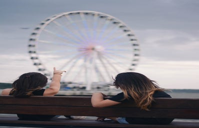 Girls on bench in front of ferris wheel