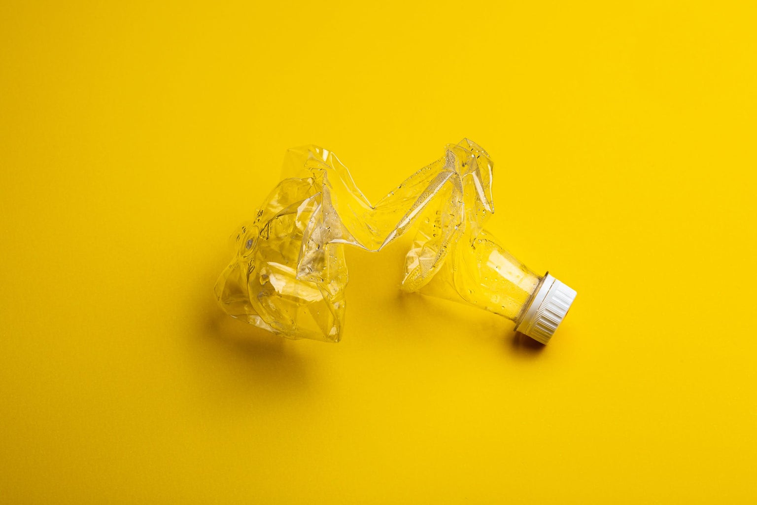 plastic bottle crushed against yellow background