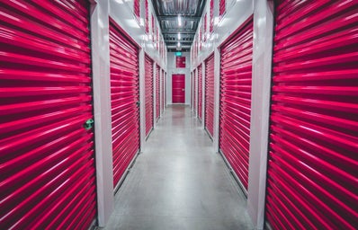 a hallway in a storage facility with purple rolling doors lining each side.