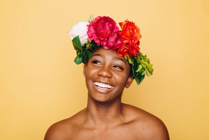 African american woman smiling against yellow background wearing flower crown