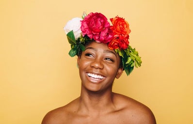 African american woman smiling against yellow background wearing flower crown