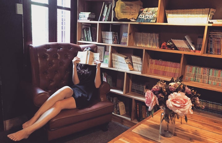 Woman hiding her face with a book in a library wearing a dress
