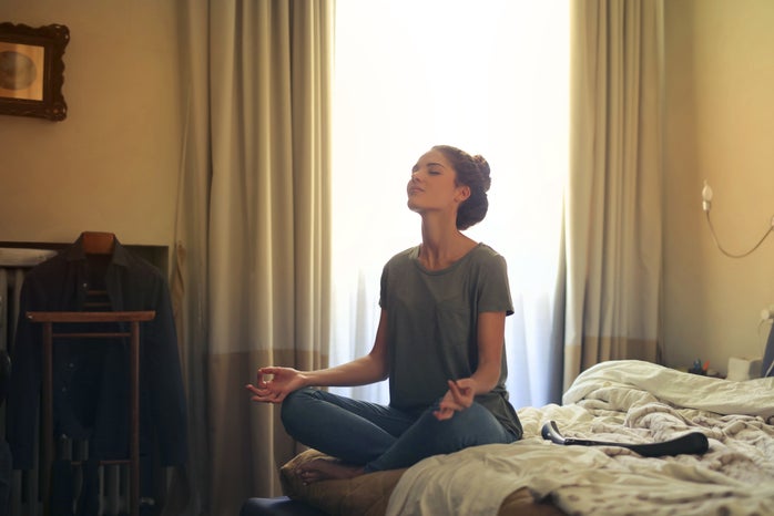 Woman meditating in bedroom