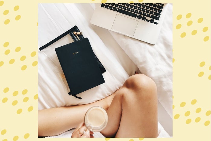 person holding coffee cup working from bed
