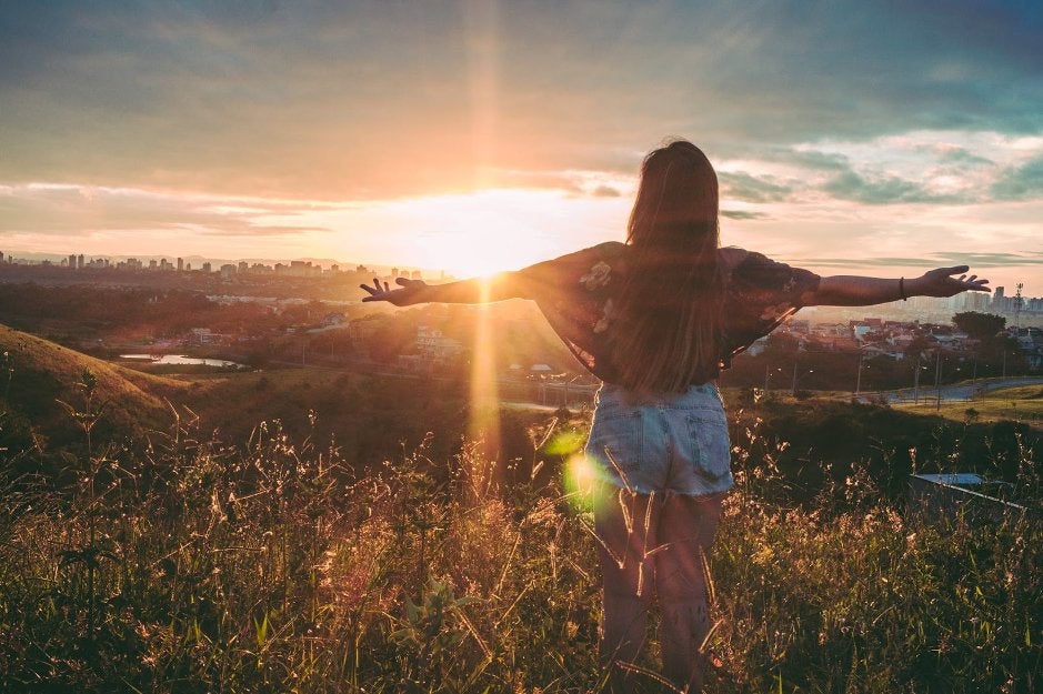 person standing on field facing a sunset