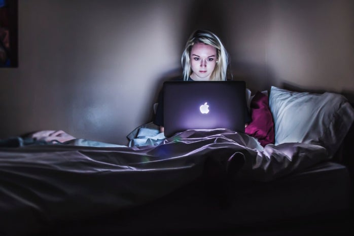 woman sitting on bed with MacBook on lap