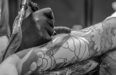 grayscale photo of person applying tattoo 955938jpg?width=398&height=256&fit=crop&auto=webp