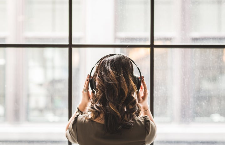 Woman Listening on Headphones Facing a Window