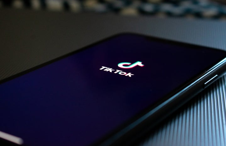 A phone sitting on a table displaying the TikTok logo on the screen