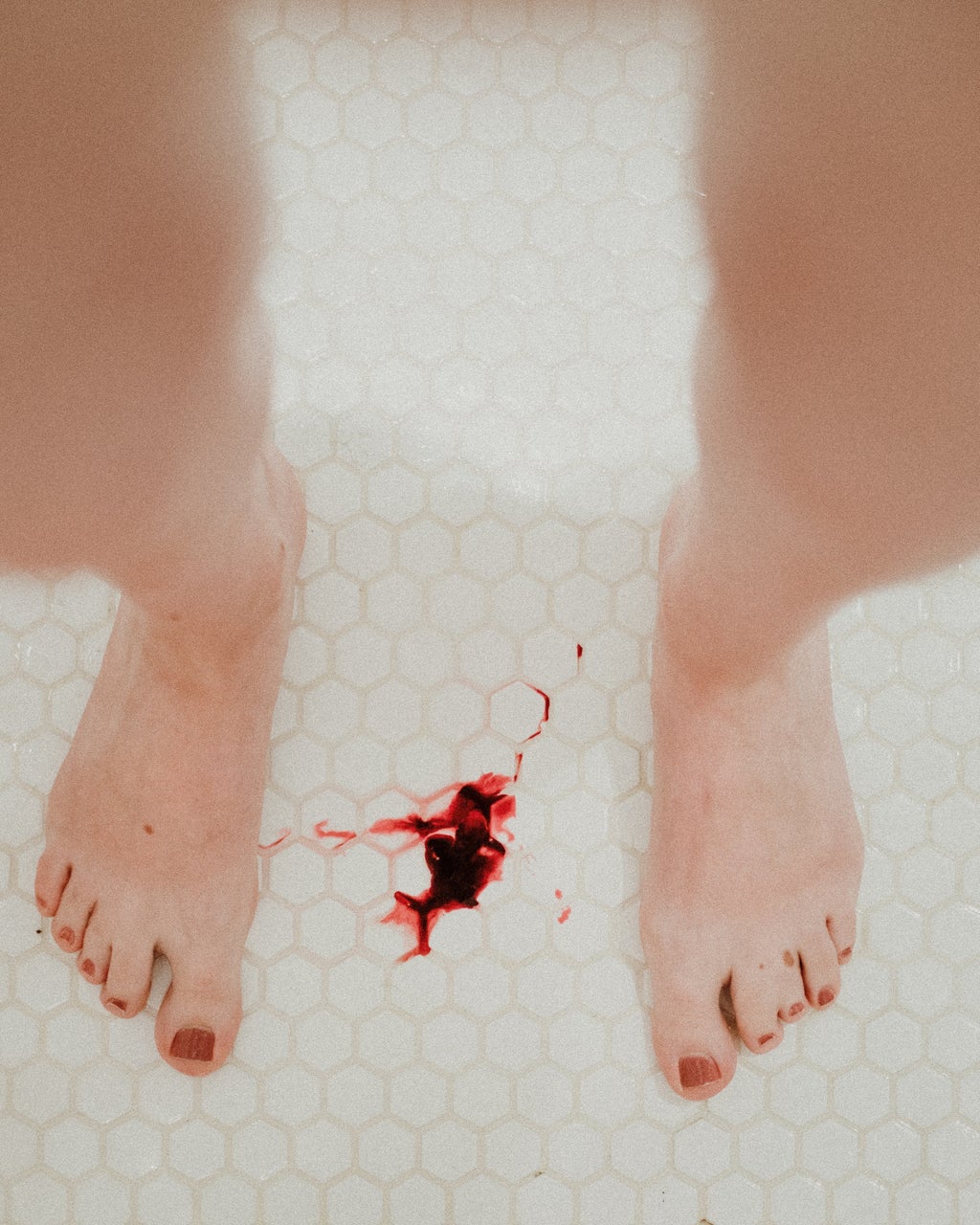 Feet standing in shower with blood on the floor