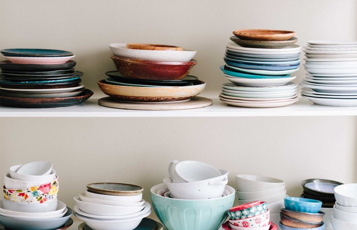 two shelves stacked with plates and bowls of a variety of colors