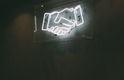 a black and white photo of a neon sign of two hands shaking