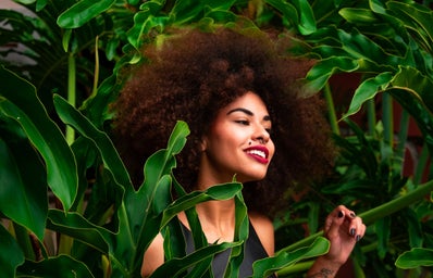 Woman with afro surrounded by plants