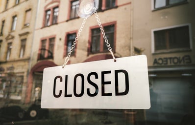 A white sign that says \"Closed\" in a window reflection
