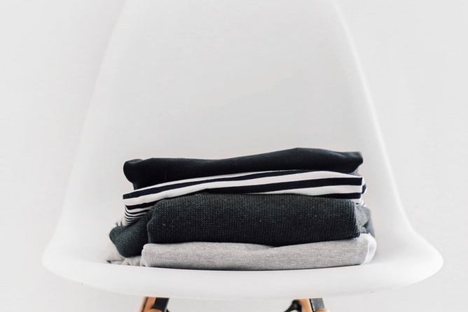 small stack of folded back and white clothing sitting atop a white chair against a white backdrop