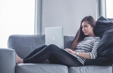 woman sitting on the sofa while using a laptop
