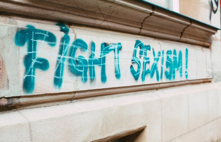 white background wall with graffiti with fight sexism written